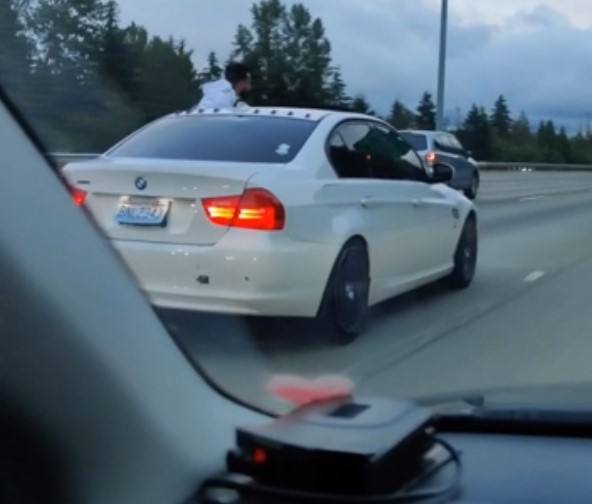 tài xế BMW 3-Series vừa lái xe vừa ngồi trên cửa sổ