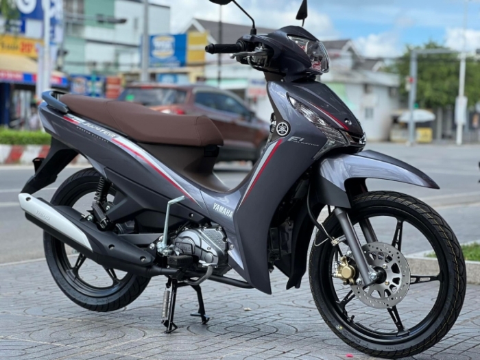 Sau khi được mở bán, Yamaha Jupiter Finn 2022 đã thu hút được nhiều sự chú ý của khách Việt và hút khách không kém đối thủ Honda Future. Chính điều này đã khiến giá bán của Yamaha Jupiter Finn 2022 chênh cao đáng kể so với giá niêm yết của hãng, thậm chí cao hơn tới 7 triệu đồng tại nhiều đại lý. Tuy nhiên, bước sang giữa tháng 8, giá xe Yamaha Jupiter Finn 2022 đã bất ngờ giảm mạnh, xuống mức chỉ còn ngang giá niêm yết của hãng. Theo đó, các phiên bản của Yamaha Jupiter Finn 2022 đang được bán ra với mức giá lần lượt là 27,5 triệu đồng đối với bản tiêu chuẩn và 28 triệu đồng đối với bản cao cấp. Mức giá này của Yamaha Jupiter Finn 2022 rõ ràng là “dễ thở” hơn so với đối thủ Honda Future. Sau khi giá xe Yamaha Jupiter Finn 2022 giảm mạnh, số lượng xe tại các đại lý hiện không còn nhiều. Theo khảo sát tại một đại lý ở Hà Nội, Yamaha Jupiter Finn 2022 hiện đang “cháy hàng” và không còn chiếc xe nào sẵn có. Chưa kể, cứ xe về là lại có khách đặt cọc luôn khiến nhiều người chưa thể mua Yamaha Jupiter Finn 2022 ngay trong thời điểm này. Đây được xem là tín hiệu tích cực của một tân binh mới gia nhập phân khúc xe số tại Việt Nam – nơi mà các dòng xe của Honda đang “làm mưa làm gió”. Khi mới ra mắt, Yamaha Jupiter Finn 2022 đã gây tranh cãi vì sở hữu thiết kế có nhiều điểm tương đồng với đối thủ Honda Future. Tuy nhiên, Yamaha Jupiter Finn 2022 lại chinh phục được khách Việt nhờ khả năng vận hành bền bỉ và tiết kiệm nhiên liệu ấn tượng. Với khối động cơ dung tích 113,7cc, Yamaha Jupiter Finn 2022 có công suất 9 mã lực cùng khả năng tiết kiệm nhiên liệu 1,64L/100 km. Chưa kể, Yamaha Jupiter Finn 2022 còn là mẫu xe số đầu tiên tại thị trường Việt được trang bị hệ thống phanh kết hợp UBS giúp cân bằng lực phanh tốt hơn. Ngoài ra, những tính năng đáng chú ý khác trên Yamaha Jupiter Finn 2022 còn có cốp đựng đồ rộng rãi bên dưới yên xe, hộc đựng đồ hay cổng sạc USB.